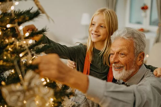 Grandad and granddaughter decorating a Christmas tree