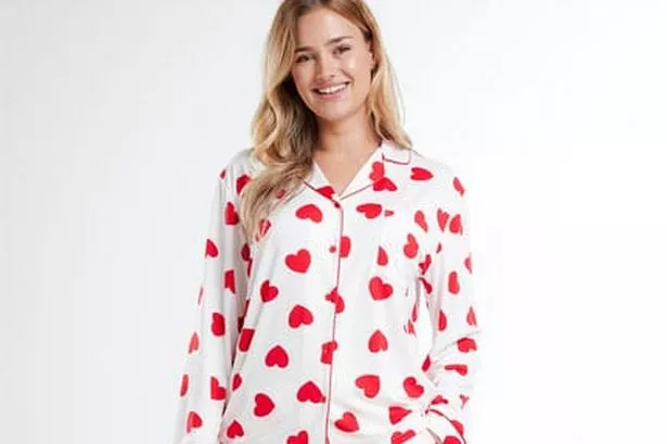 Woman wears white long-sleeve PJs with red heart pattern