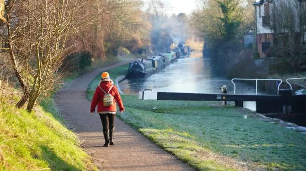 A woman walks along the towpath beside the Kennet and Avon Canal in Devizes, Wiltshire