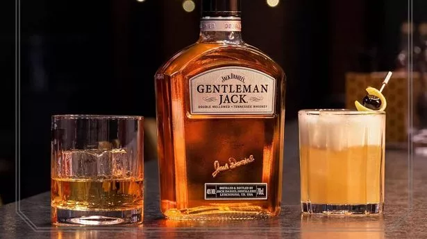 A bottle of Gentleman Jack whiskey next to glasses.