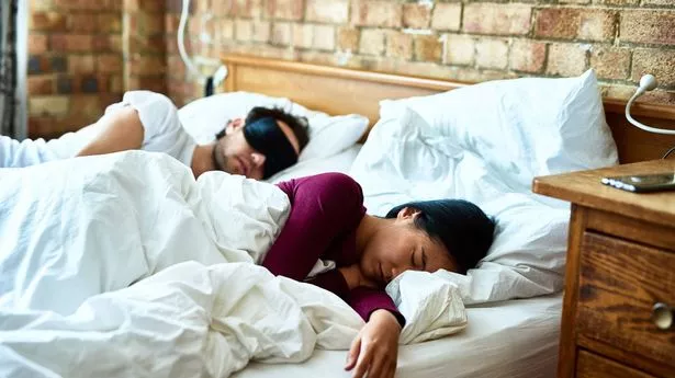 Couple sleeping in bed, hotel room in daylight, jet lagged from traveling