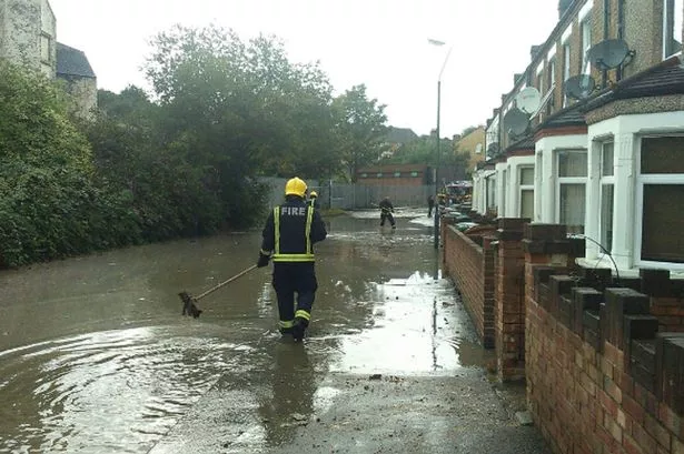 A firefighter walking along a street flooded by sewage in south London