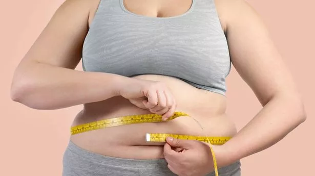 Woman measuring her waist with a tape measure.