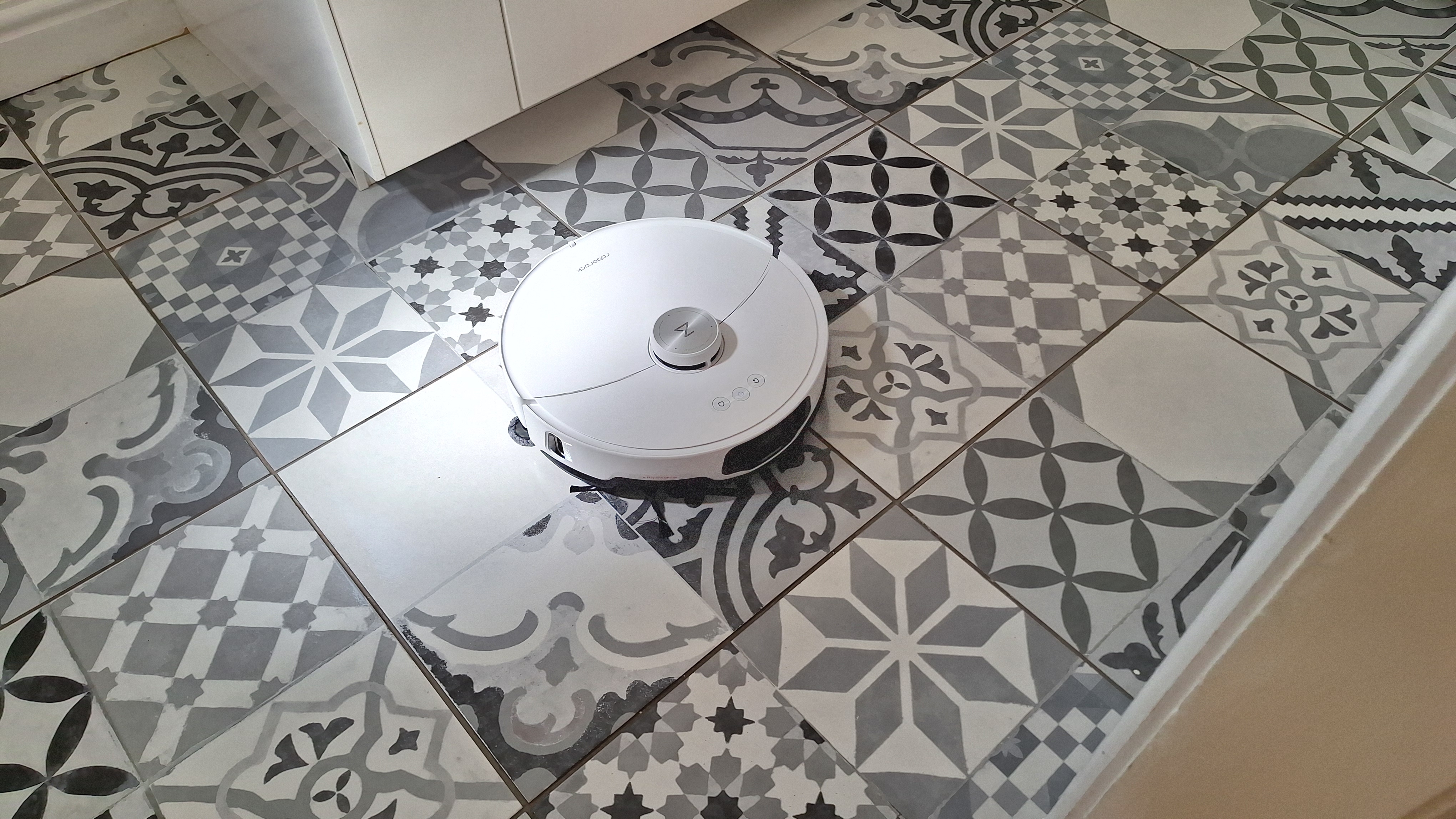 A top view of the Roborock S8 MaxV Ultra mopping a grey and white tiled floor. 