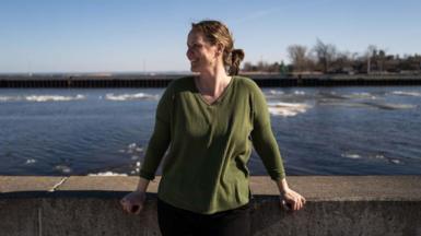 Christina Welch wears a green sweater while standing near the water in Deluth