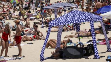 Beachgoers are seen on the sand on Christmas Day at Bondi Beach in Sydney on December 25, 2024