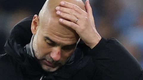 Pep Guardiola with his head in his hands looking dejected