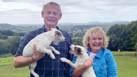 Martin Clunes and Martha Kearney holding two dogs