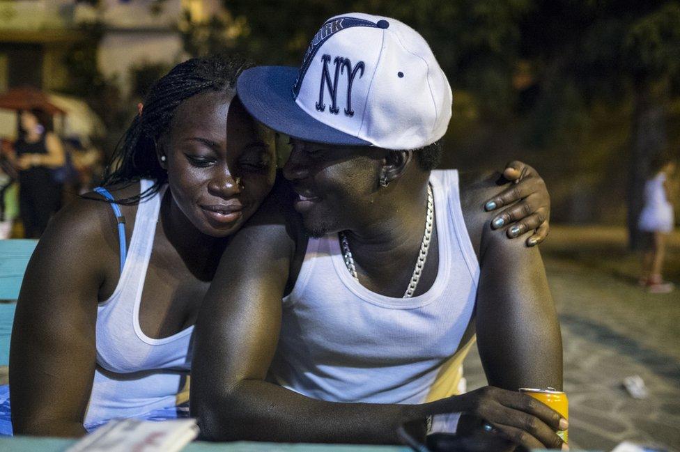 Gambians Shiriffo and Eva are newly married. They fled Gambia due to the dictatorship and lack of jobs. They are grateful to the Mayor but also struggling to find work in the Riace