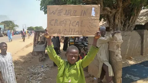 Reuters A boy holds a sign to protest against the kidnapping of nearly 300 schoolchildren this week