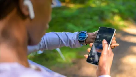 Getty Images Woman using phone, smart watch and fitness tracking software