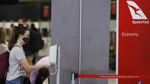 Getty Images People sanitise their hands at Melbourne Airport after checking in for flights to New South Wales, 23 November 2020