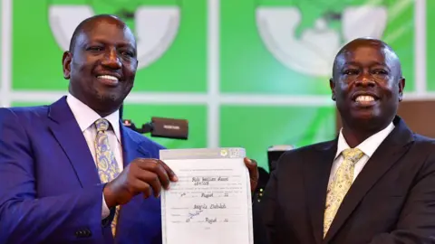 Both wearing suits, William Ruto stands with Rigathi Gachagua holding a certificate of election between them in an archive picture from 2022.