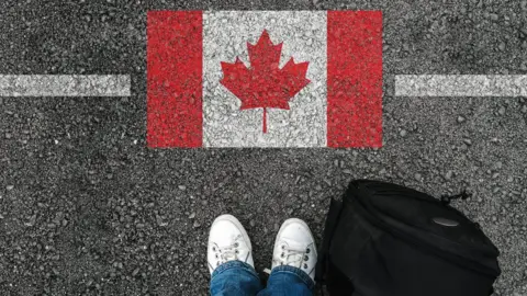 Getty Images Person in front of a picture of a Canadian flag