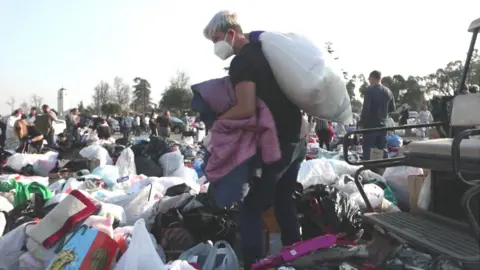 Man walking among piles of donated goods 