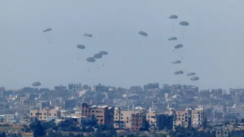 Reuters Aid is dropped by a plane over Gaza, as seen from Israel (13 March 2023)