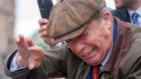 PA Media Nigel Farage holds his hand over his face