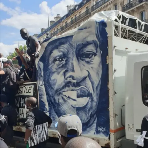 Half of George Floyd's face appears at a rally in Paris