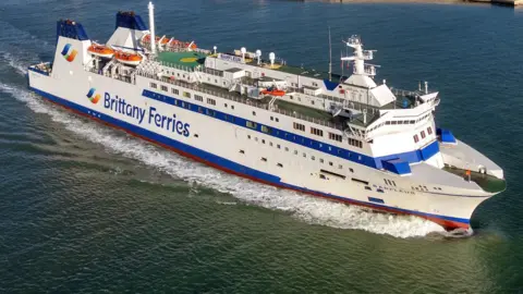 A Brittany Ferries vessel under sail on a calm sea.