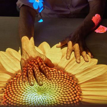 An elder woman interacts with table projection content