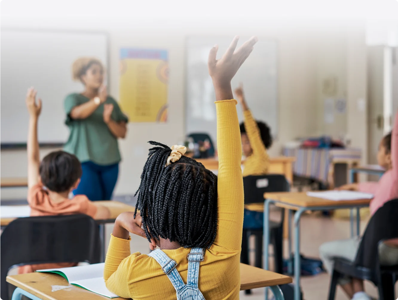 A TELUS Wise educator facing a classroom full of children raising their hands