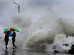 People hold their umbrellas as they walk on an embankment against gusty winds and high waves in Chennai on Friday. (AP)