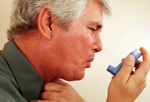 Man holding inhaler while having an asthma attack.