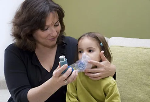 Mother helping daughter with her asthma inhaler.