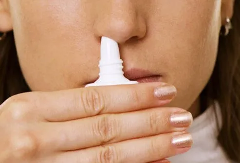 A woman using nasal spray.