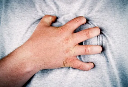 A man with indigestion pain grips his chest.