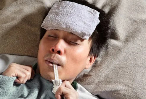 A man with a thermometer in his mouth suffers from a fever.