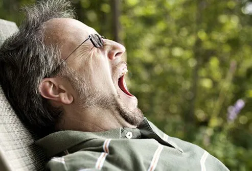 A middle-aged man yawns from fatigue.