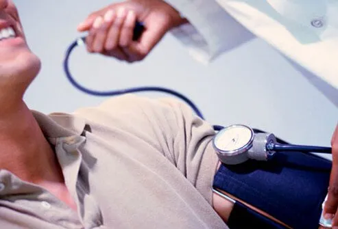 A male patient has his blood pressure checked by a doctor.