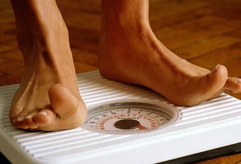 A woman checks her weight on a scale.