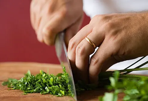 A woman chops herbs for cooking.