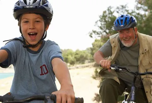 A grandfather and his grandson have fun riding their bikes.