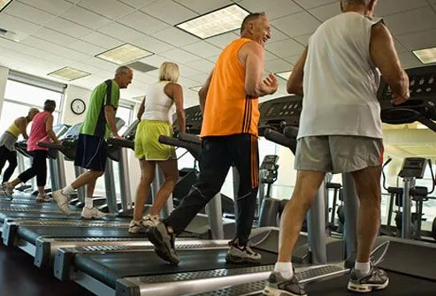 A group of people walk on treadmills.