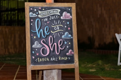 brown framed chalkboard easel with baby coming in July he or she text