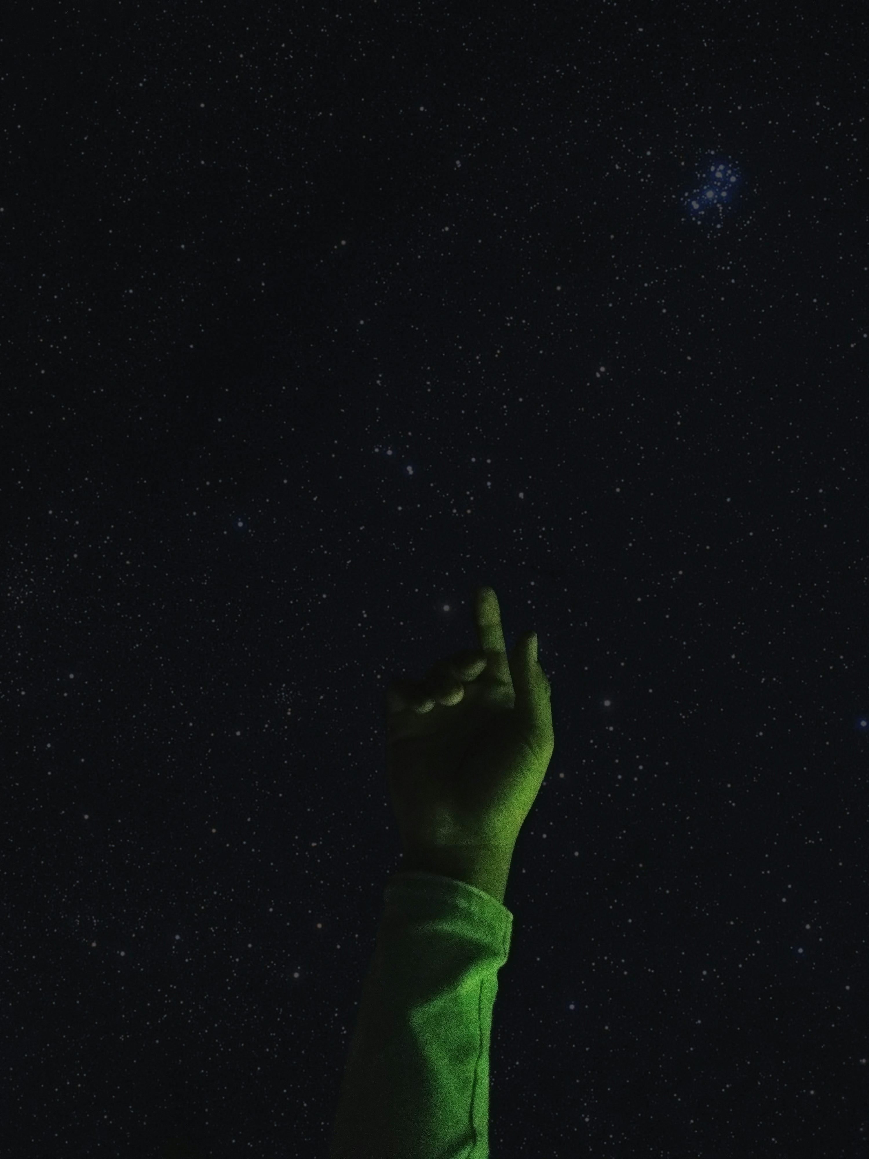una mano protesa verso il cielo di notte
