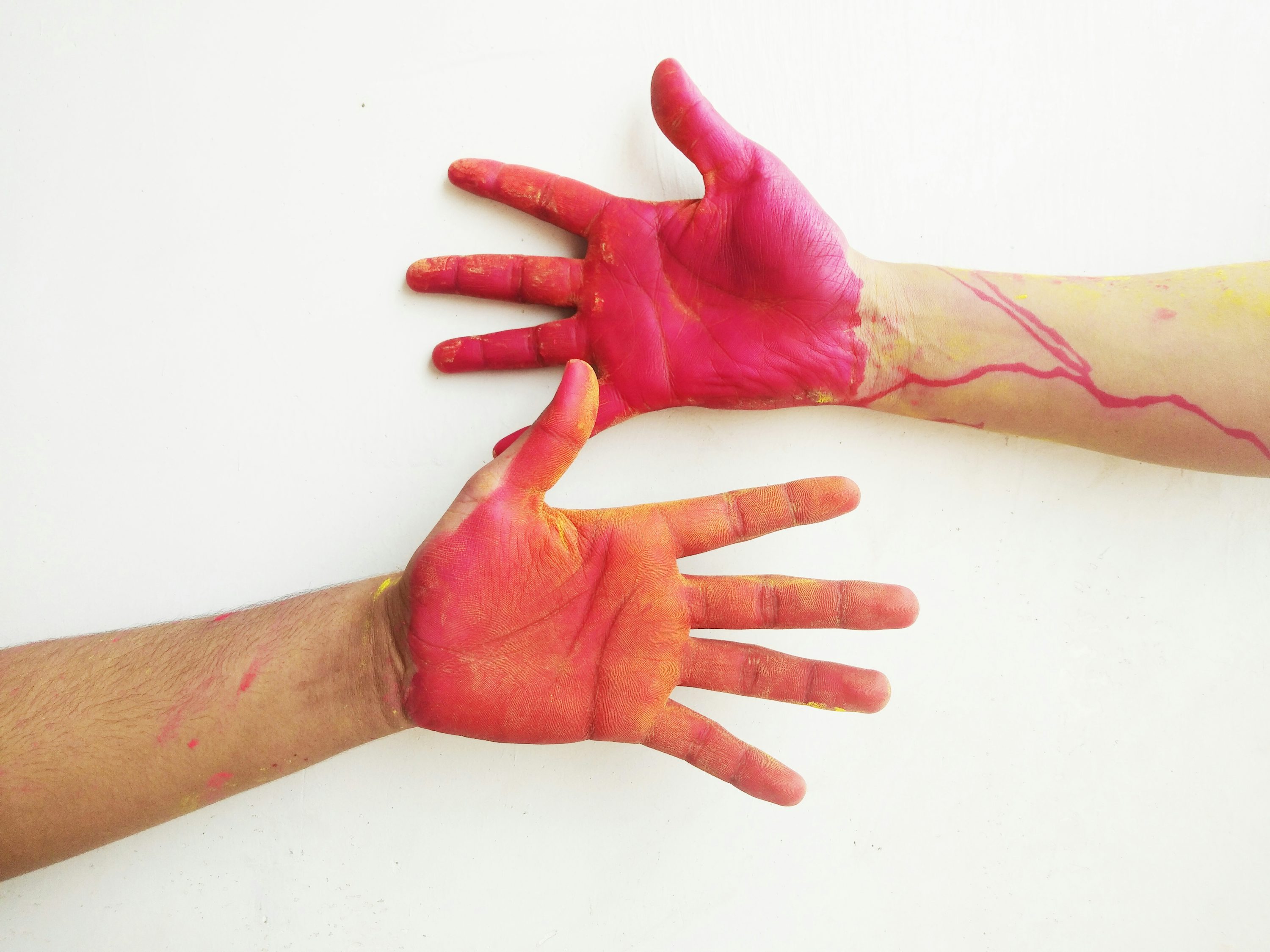 zwei Hände mit roter und gelber Farbe darauf
