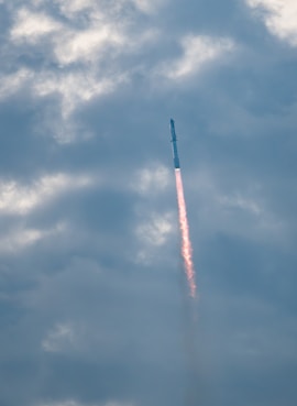 a jet flying through a cloudy blue sky