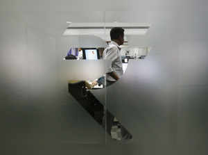 A currency trader is pictured through the symbol for the Indian Rupee on the floor of a trading firm in Mumbai