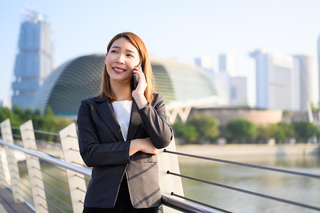 Photo portrait of smiling young woman standing on railing in city