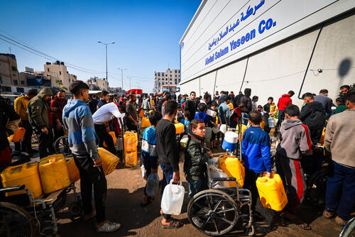 A group of displaced Palestinians waits in front of Abed Al-Salam Yassin company in the Tal Al-Sultan area of the southern Gaza town of Rafah.