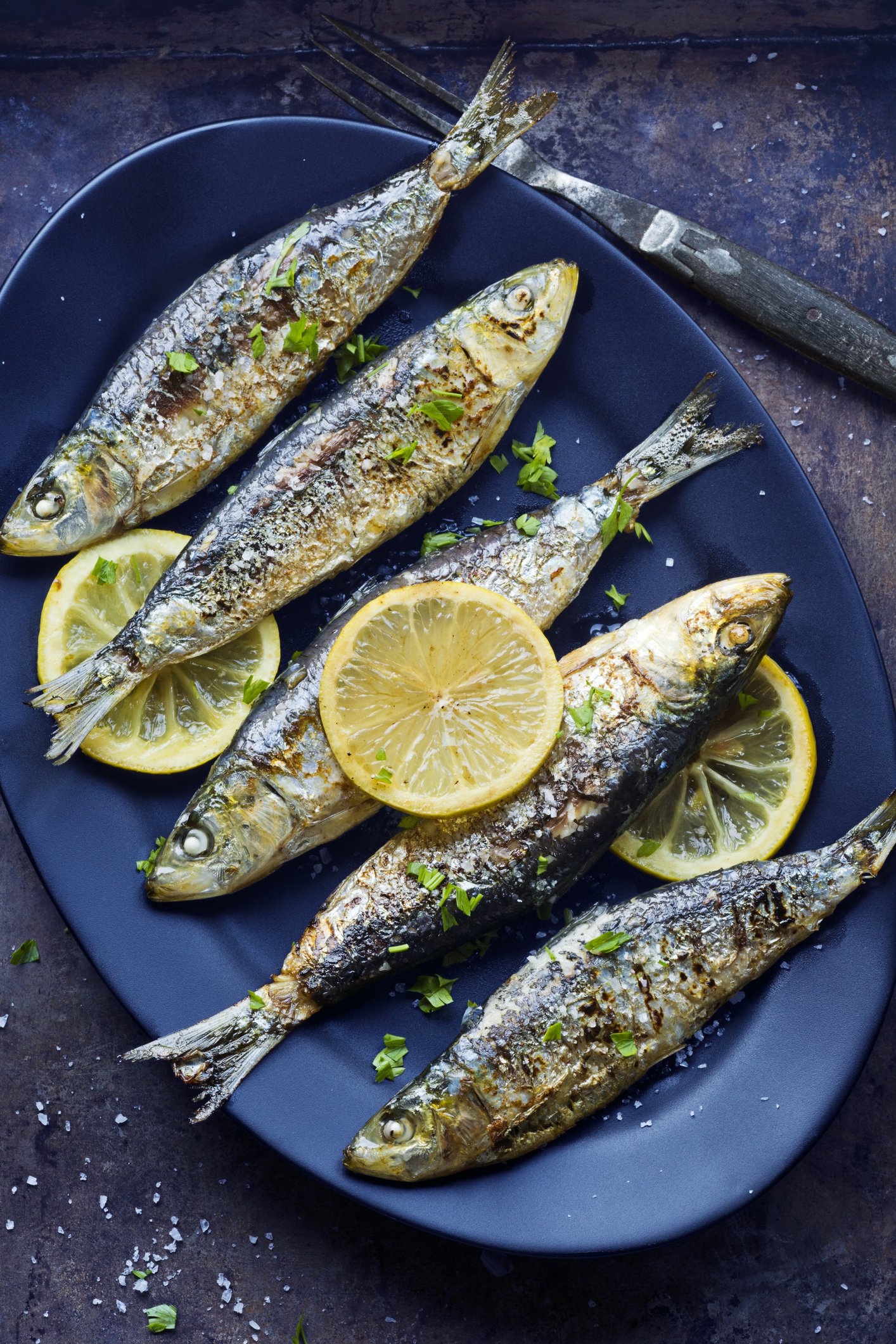 Portuguese sardines are rolled in salt and grilled over an open flame. These are served with parsley and grilled lemon slices. This photo works well as both a vertical and a horizontal image. Portuguese Grilled Sardines Recipe from Miele Der Kern Image via Katherine Mathews