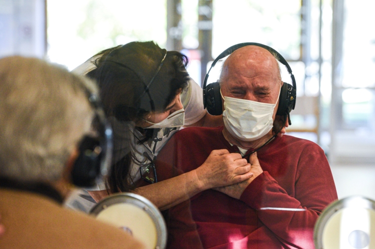 A resident (R) reacts as he talks to his visiting sister (L) at the Domenico Sartor nursing home in Castelfranco Veneto, near Venice, on November 11, 2020 through a glass and plastic device in a so-called "Hug Room" amid the new coronavirus pandemic. - The Hug Room allows guests and their families to embrace each other, while remaining separate and protected from the contagious disease, still guaranteeing physical contact for mental and emotional wellbeing. (Photo by Piero CRUCIATTI / AFP) (Photo by PIERO CRUCIATTI/AFP via Getty Images)