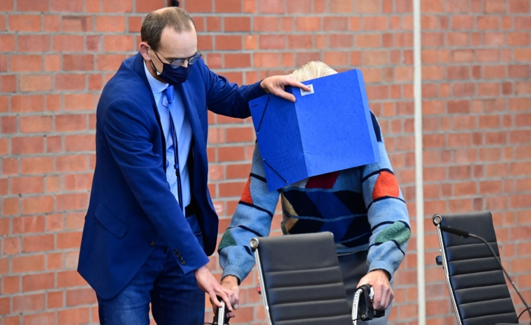 TOPSHOT - Defendant Josef S gets help from his lawyer Stefan Waterkamp (L) to hide his face behind a folder as he arrives for his trial in Brandenburg an der Havel, northeastern Germany, on October 7, 2021. - The 100-year-old former concentration camp guard will become the oldest person yet to be tried for Nazi-era crimes in Germany when he goes before court charged with complicity in mass murder. The suspect, identified as Josef S., stands accused of "knowingly and willingly" assisting in the murder of 3,518 prisoners at the Sachsenhausen camp in Oranienburg, north of Berlin, between 1942 and 1945. (Photo by Tobias Schwarz / AFP) (Photo by TOBIAS SCHWARZ/AFP via Getty Images)