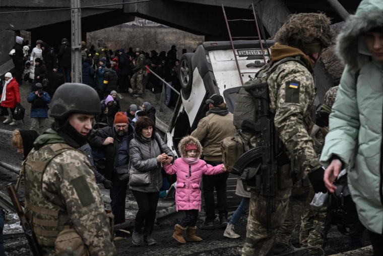 People cross a destroyed bridge as they evacuate the city of Irpin, northwest of Kyiv, during heavy shelling and bombing on March 5, 2022, 10 days after Russia launched a military in vasion on Ukraine. (Photo by Aris Messinis / AFP) (Photo by ARIS MESSINIS/AFP via Getty Images)