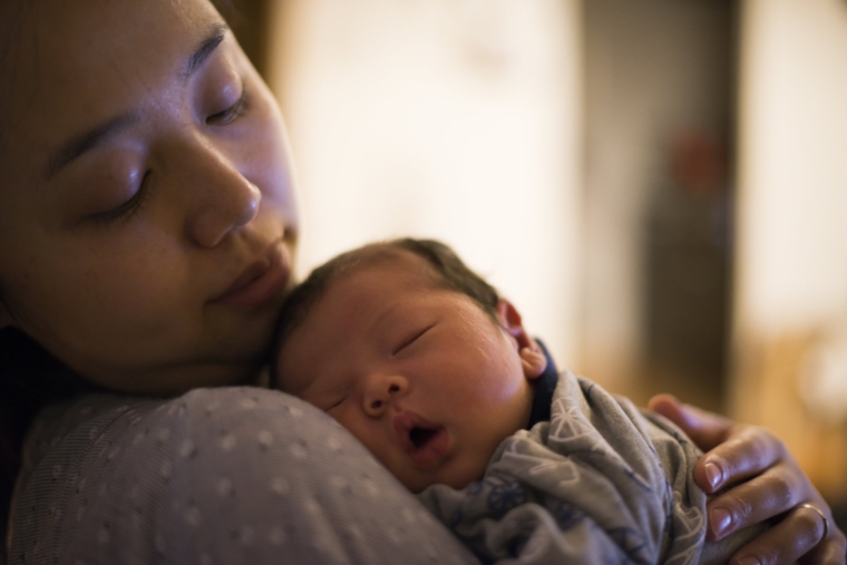 A mother looks his newborn baby gently.