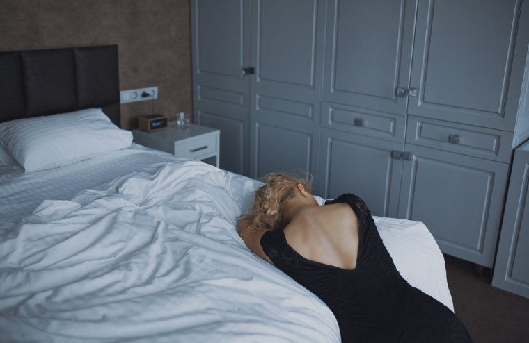 Rear view of a crying woman lying on bed in despair.